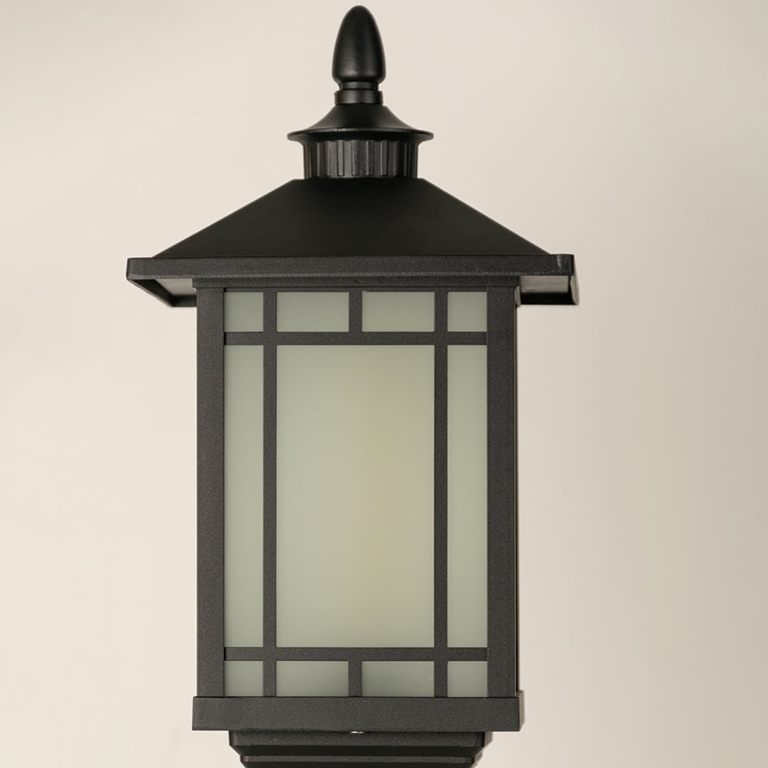 A closeup of the outdoor pillar lamp focusing on the frosted glass light chamber and geometric framing that creates a modern clean lined lighting aesthetic.