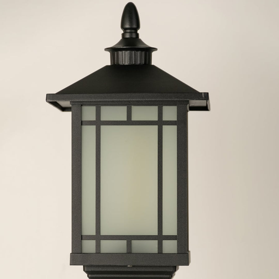 A closeup of the outdoor pillar lamp focusing on the frosted glass light chamber and geometric framing that creates a modern clean lined lighting aesthetic.