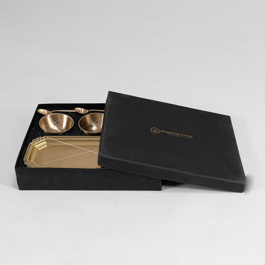 Brass serving set with three bowls on rectangular tray shown front-facing with spoons placed inside each bowl.