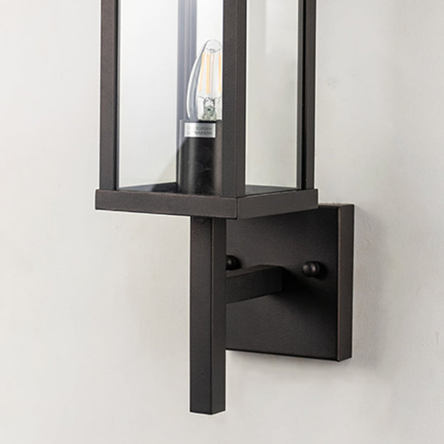 Closeup of outdoor wall light with black rectangular frame and glass shade designed for stylish exterior lighting.