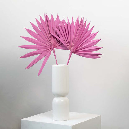 Pink dried palm leaves in tall white vase styled for modern boho home decor and table decoration.