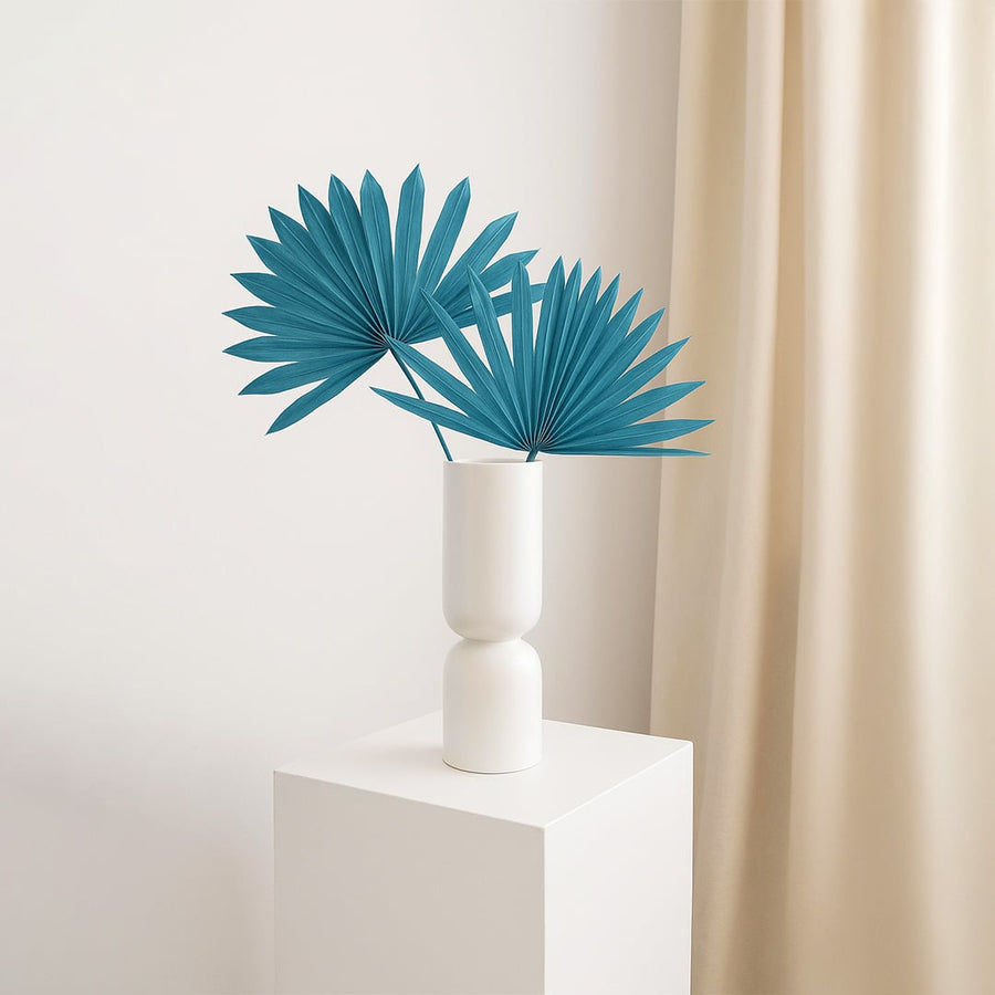 Elegant teal dried palm leaves arranged in ceramic vase bringing bold accent to home interior styling.