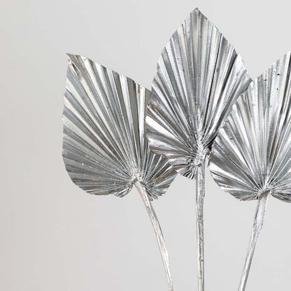 Closeup of silver dried palm leaf stems with metallic finish highlighting sharp folded texture and modern decorative appeal.