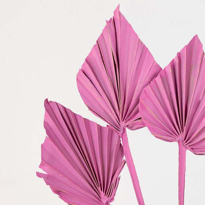Closeup of pink decorative palm leaf stem with folded fan design highlighting bold color and textured modern decor detail.