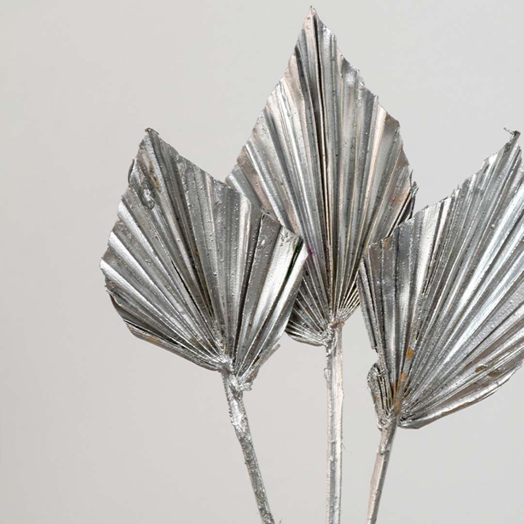 Closeup of silver metallic palm leaf stems with reflective finish adding elegant texture and modern luxury decor appeal.