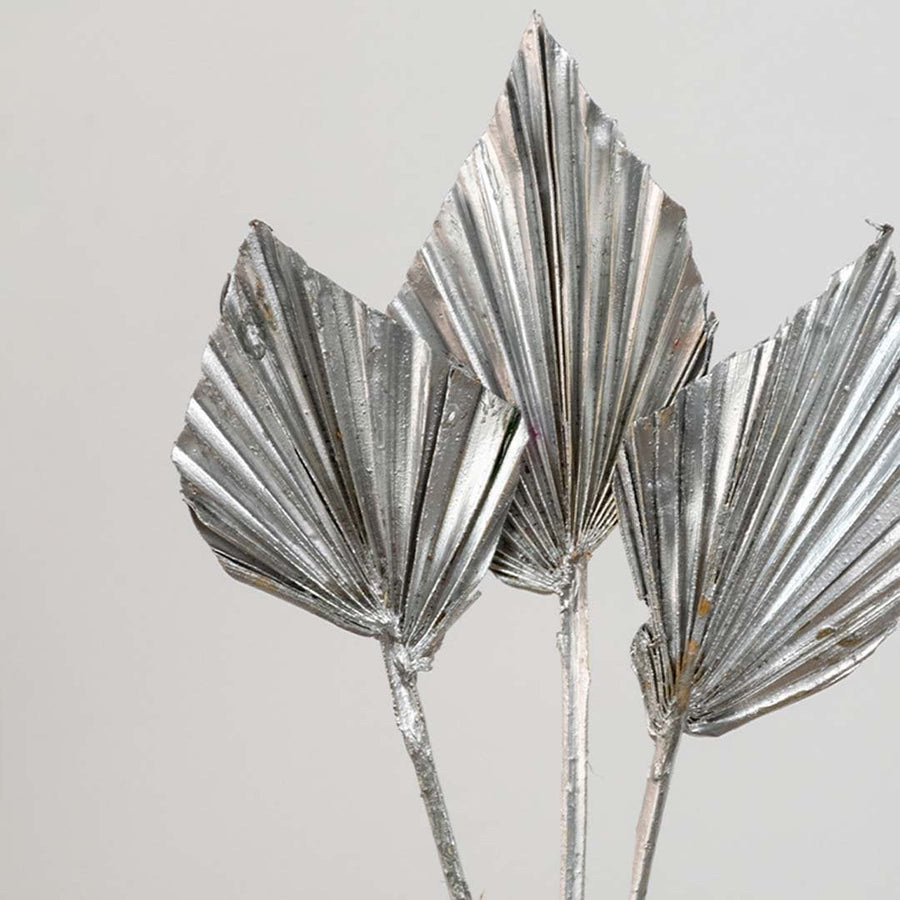 Closeup of silver metallic palm leaf stems with reflective finish adding elegant texture and modern luxury decor appeal.