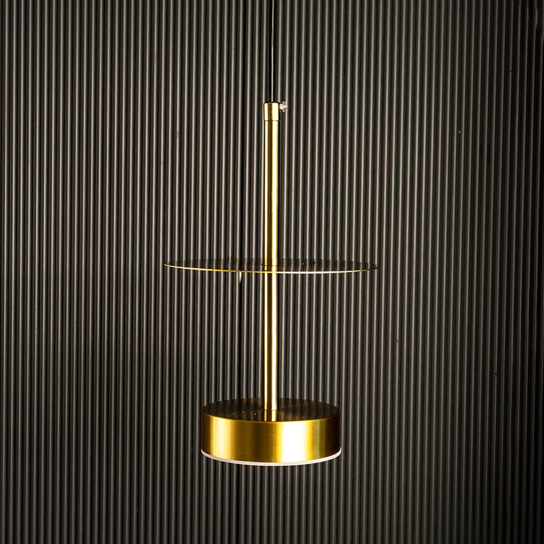 Halo brass pendant light turned on showing minimal ring-shaped brass design against white background.