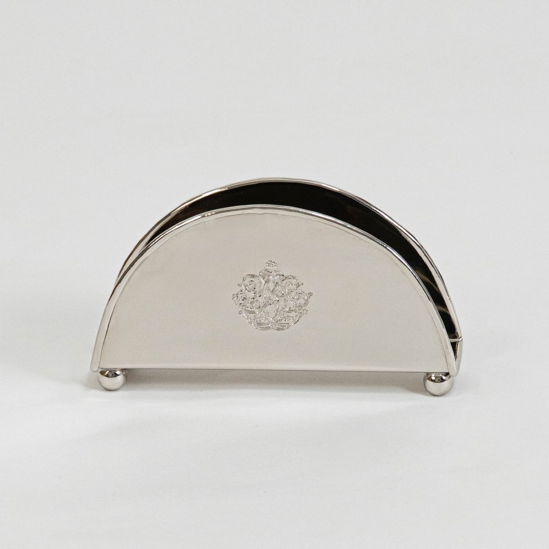 Half-round brass napkin holder with floral crest placed on white background showcasing finish and elegant shape.