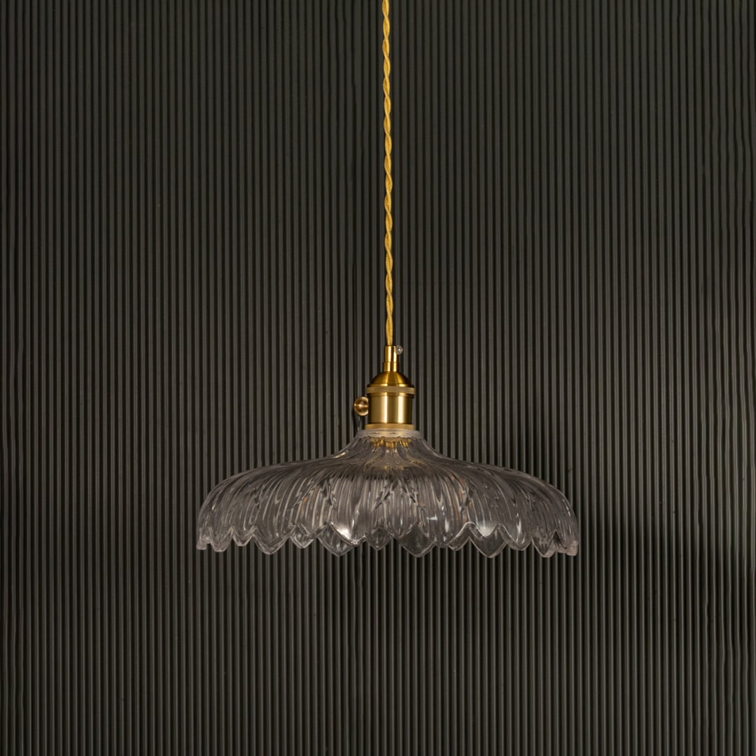 Clear ribbed glass pendant light with gold metal holder switched off on black background showcasing elegant vintage design.