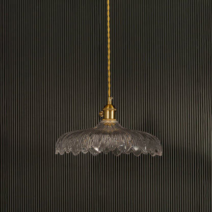 Clear ribbed glass pendant light with gold metal holder switched off on black background showcasing elegant vintage design.