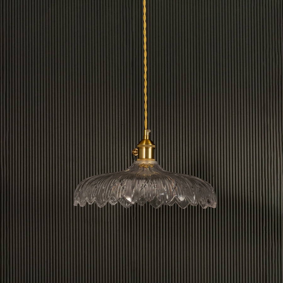 Clear ribbed glass pendant light with gold metal holder switched off on black background showcasing elegant vintage design.