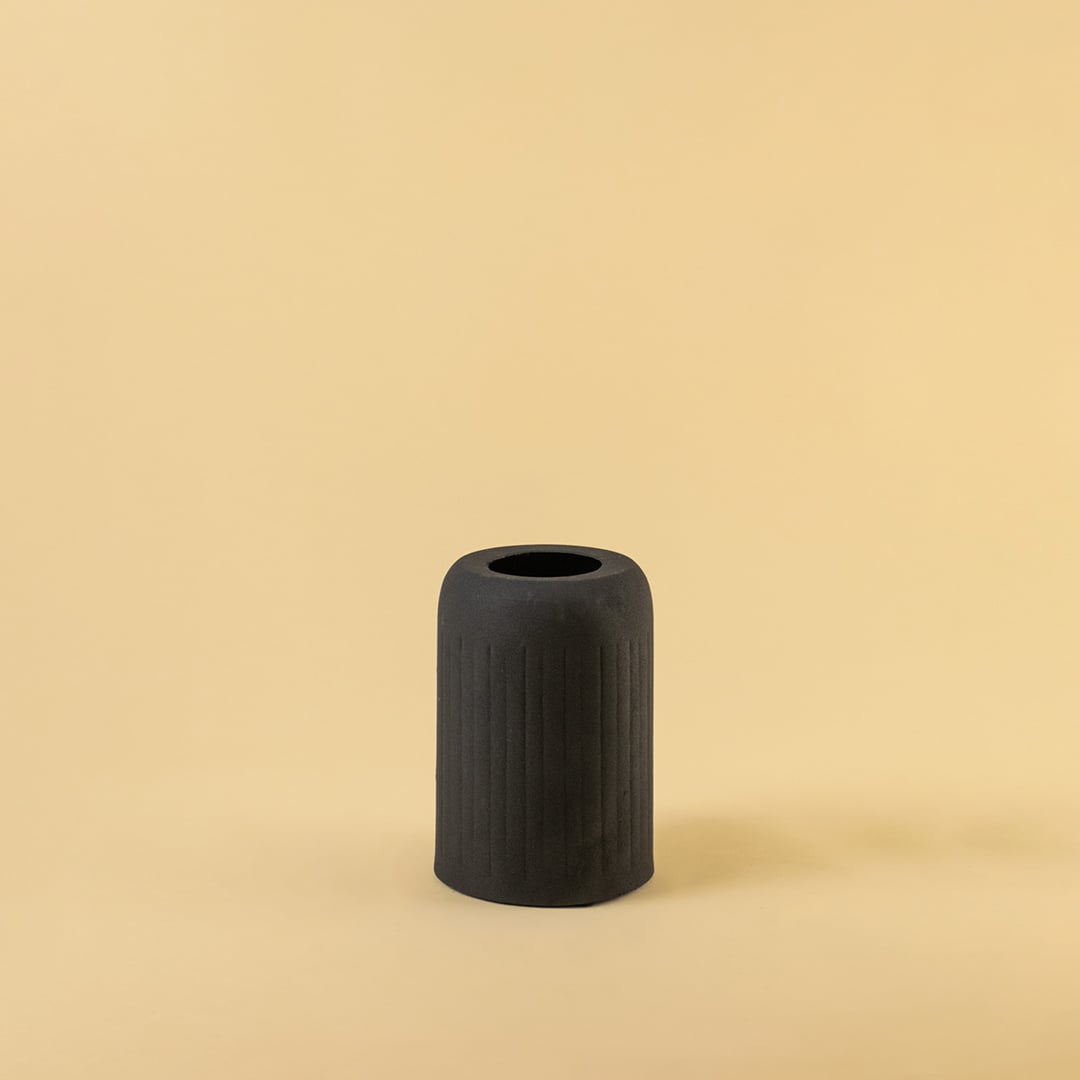 Black ribbed ceramic vase displayed on a clean white background highlighting its modern minimal and bold design.