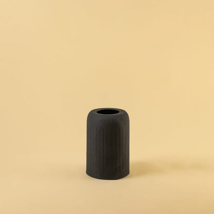 Black ribbed ceramic vase displayed on a clean white background highlighting its modern minimal and bold design.