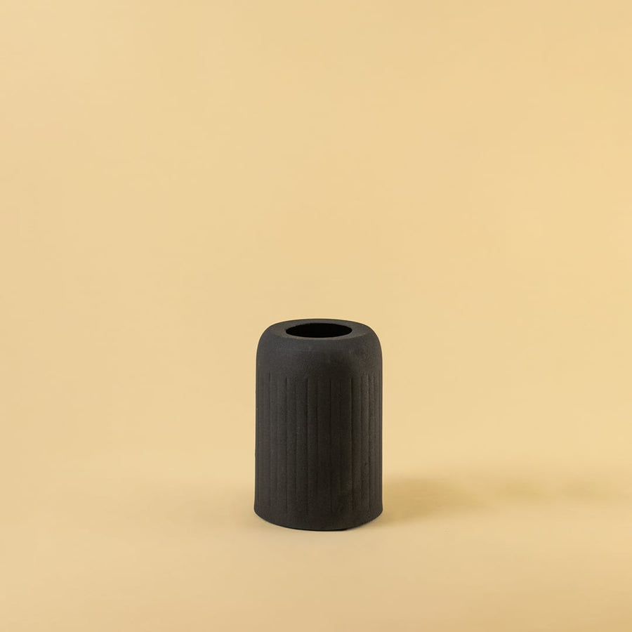 Black ribbed ceramic vase displayed on a clean white background highlighting its modern minimal and bold design.