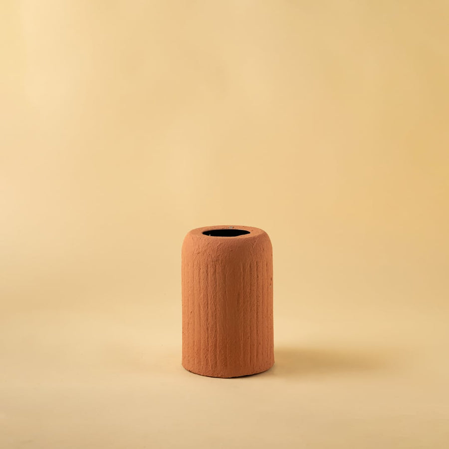 Terracotta ribbed ceramic vase displayed on a clean white background highlighting its natural warm tone and modern design.