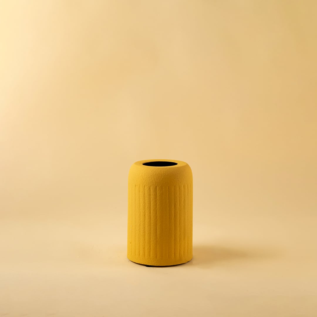 Yellow ribbed ceramic vase displayed on a clean white background highlighting its bold color and minimal modern design.