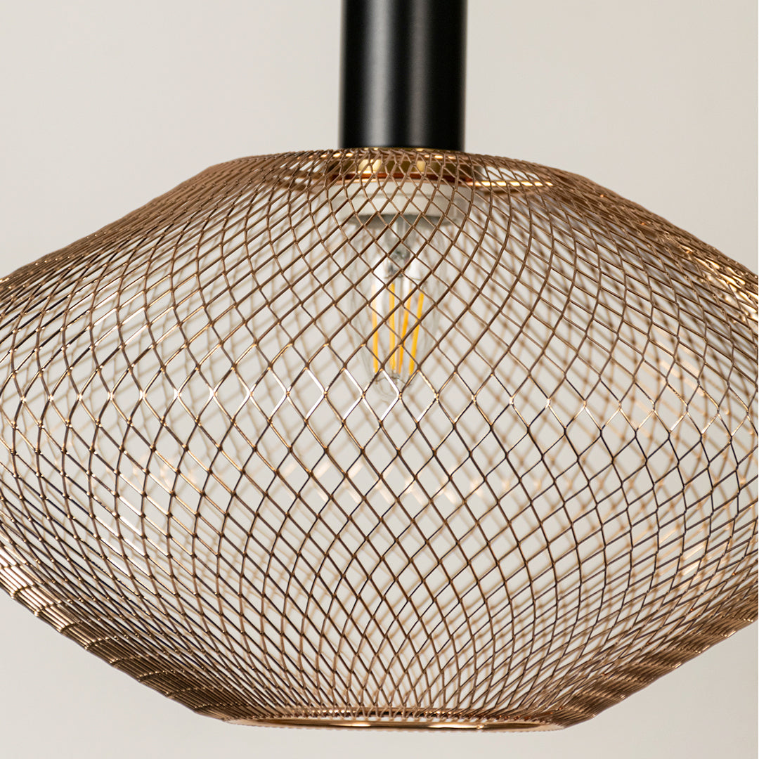 Gold metal mesh pendant light closeup showcasing intricate weave and brass detailing.