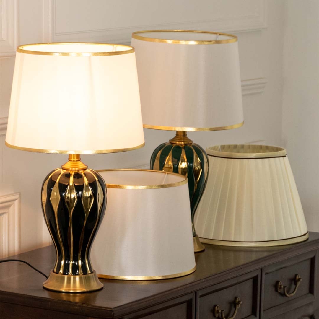 White shade black and gold ceramic table lamp on wooden sideboard with light off for classic stylish décor.