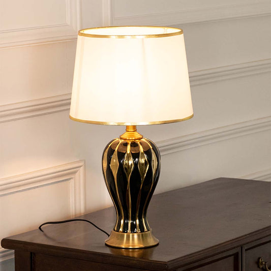 Black ceramic table lamp with fabric shade and gold accents displayed on a console table creating elegant ambient lighting.
