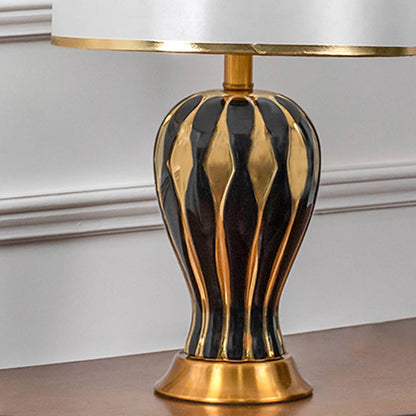 Closeup view of black gold table lamp showing premium striped design and golden base.