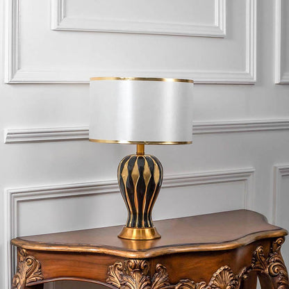 Luxury table lamp with gold metal base and white fabric shade placed on side table creating warm ambient lighting for interiors.