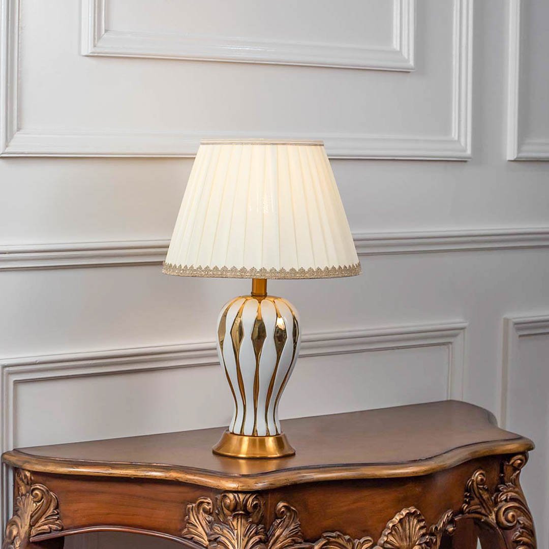 Decorative table lamp with gold metal cage base and white fabric shade on wooden console table stylish lighting for home decor.