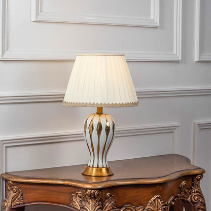 Decorative table lamp with gold metal cage base and white fabric shade on wooden console table stylish lighting for home decor.