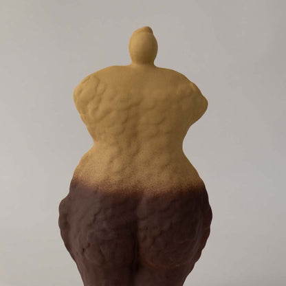 Detailed closeup of handcrafted ceramic torso sculpture vase highlighting textured finish in yellow and brown gradient tones.