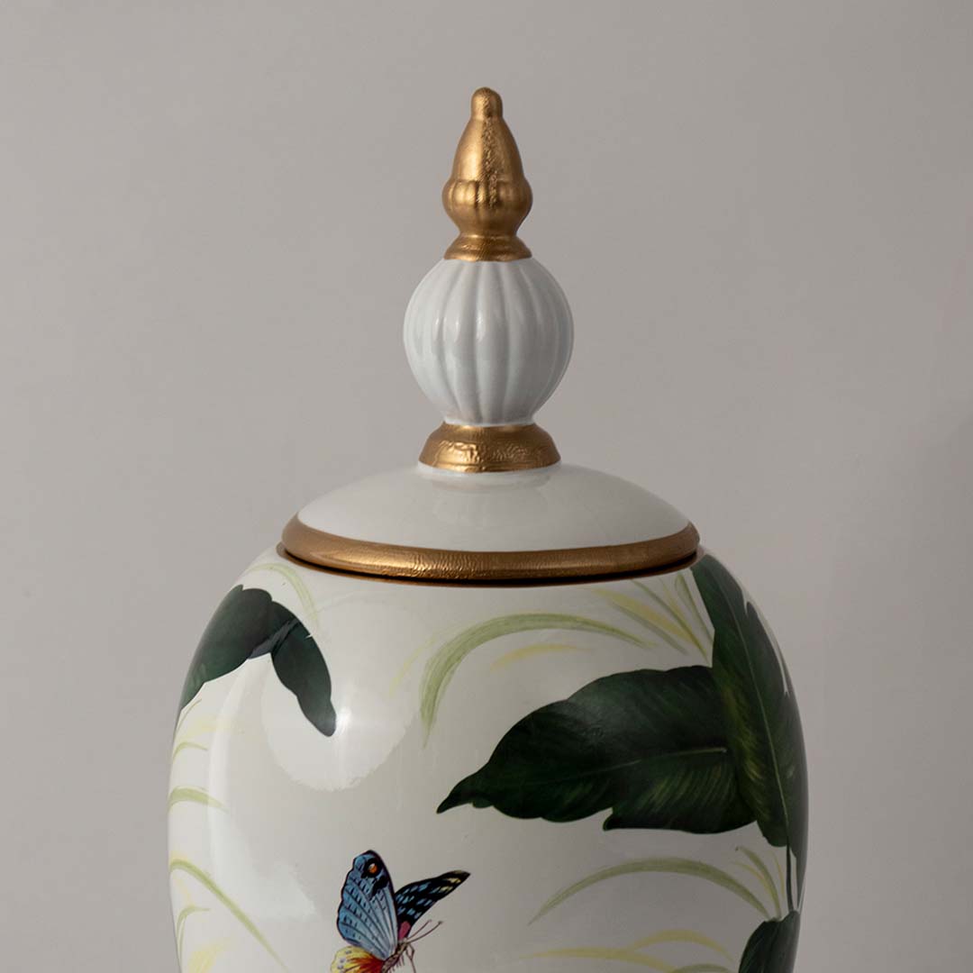 Closeup of ceramic jar showing fine green leaf detailing and glossy finish with gold accent lid and butterfly design.