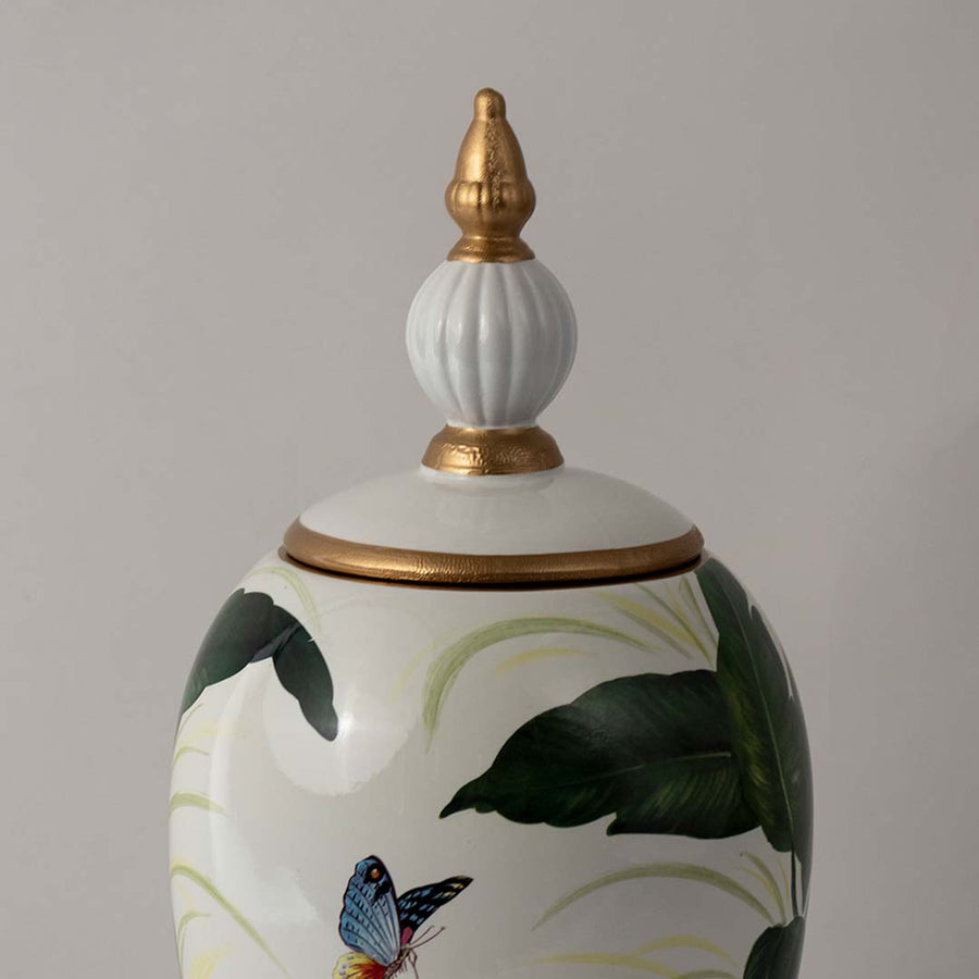 Closeup of ceramic jar showing fine green leaf detailing and glossy finish with gold accent lid and butterfly design.