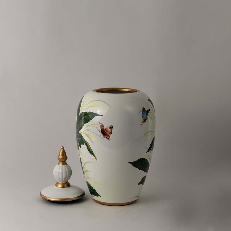 White ceramic jar with tropical green leaf design and golden lid accent perfect for elegant home interior decor.