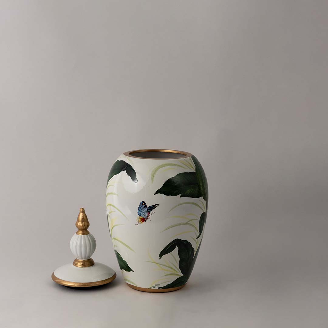 Stylish white ceramic decor jar with green botanical design and golden lid crafted for luxury home interior display.