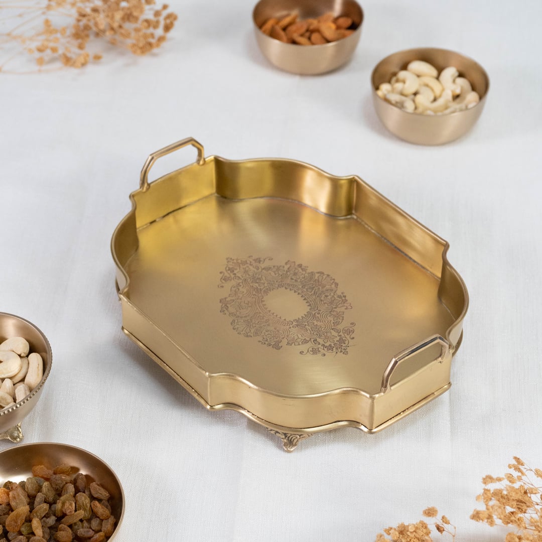 Octagonal antique gold brass tray with floral engraved center and upright handles displayed on white background.