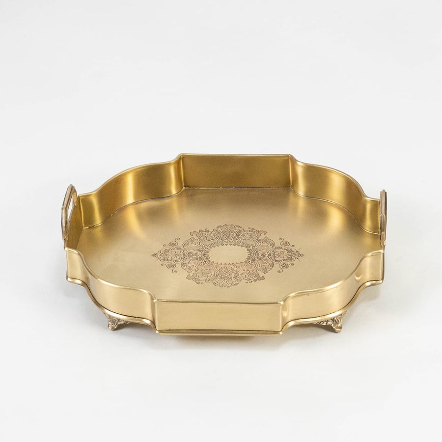 Top view of octagonal gold brass tray with floral center and high side handles placed on white plain surface.