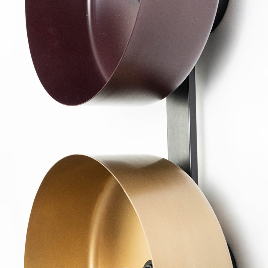 Closeup of bronze and gold metal bowl reflectors showing sleek finish and black vertical support structure.