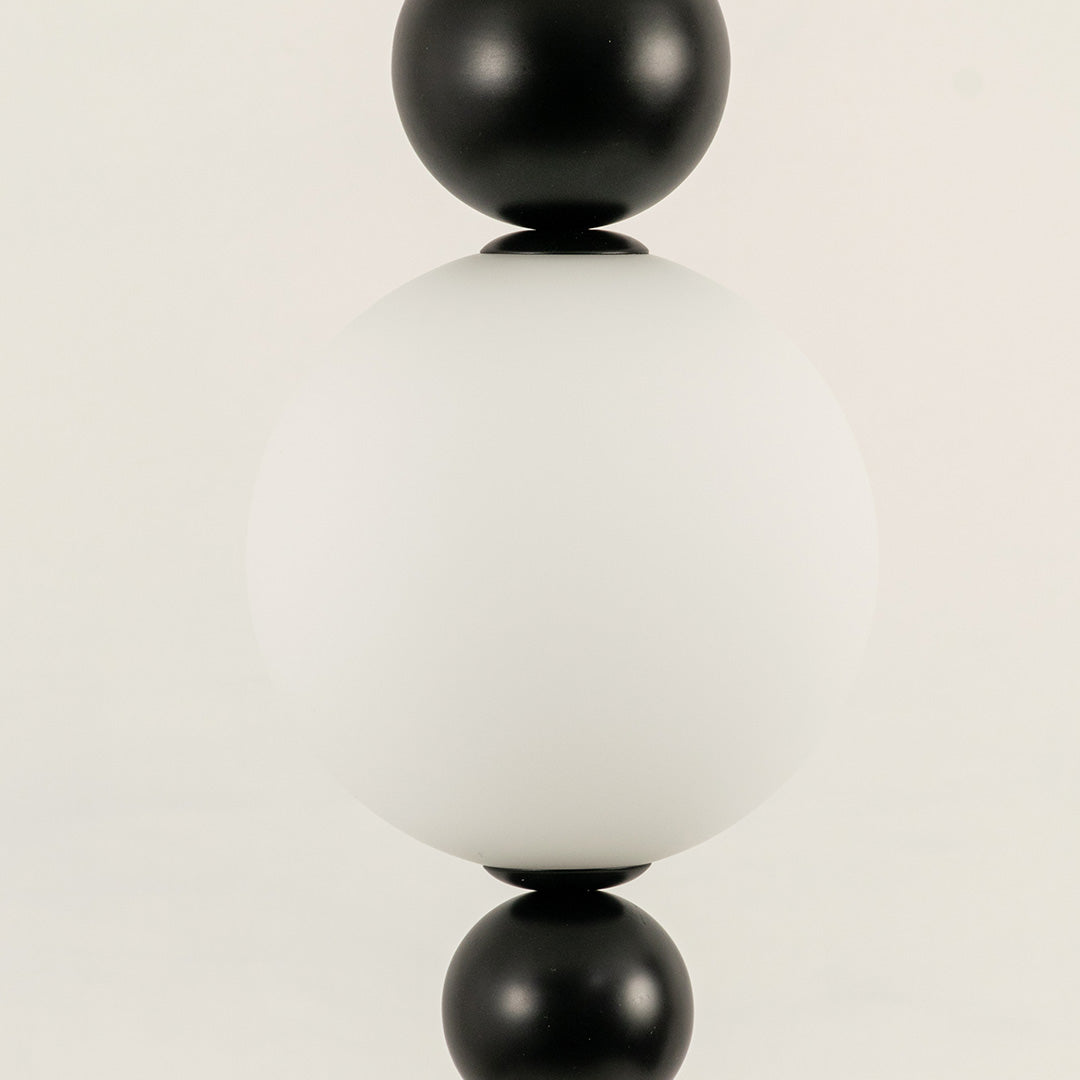 Closeup of white glass pendant light with black metal accents for elegant modern interior decor styling.