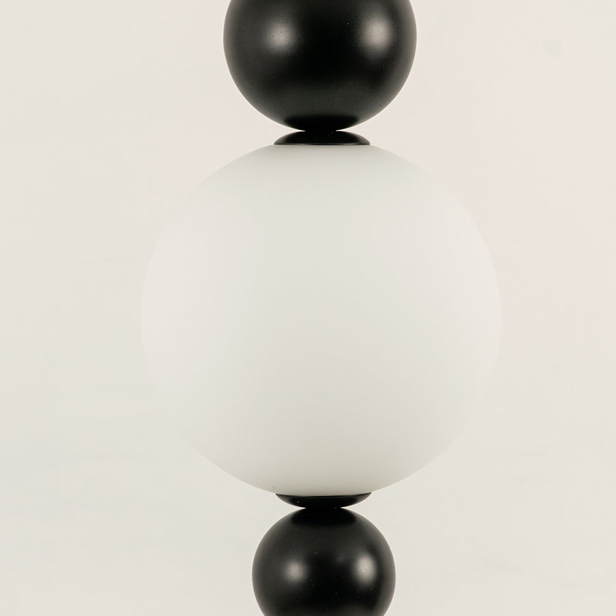 Closeup of white glass pendant light with black metal accents for elegant modern interior decor styling.