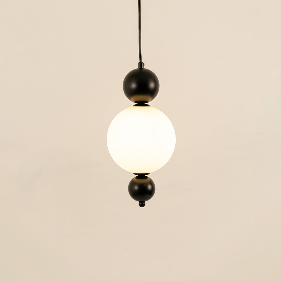 Black metal wall light with frosted glass globe illuminated to display contemporary decorative lighting elegance.