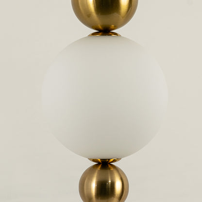 Closeup of white glass globe pendant light with gold metal accents for luxury modern interior decor styling.