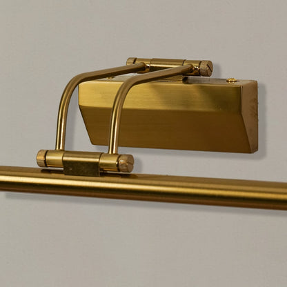 Closeup of gold metal picture light showing polished finish slim bar design and warm directional illumination.