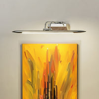 Lifestyle closeup of chrome metal picture light enhancing artwork with warm focused directional illumination.