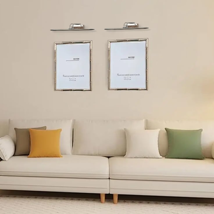 Chrome metal picture lights styled together on a modern interior wall creating bright balanced gallery style accent lighting.