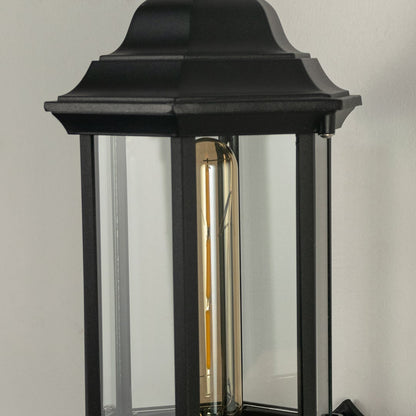 Closeup view of the black outdoor lantern showing detailed raindrop glass texture and elegant curved arm with warm light inside.