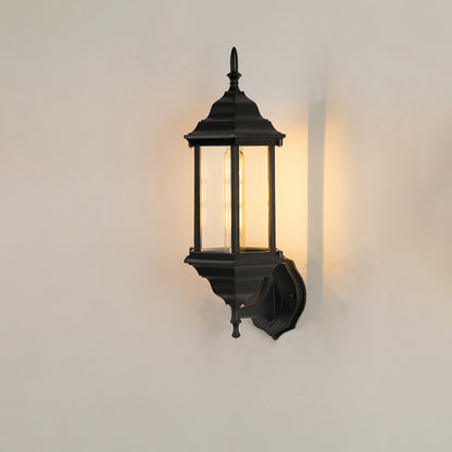 Classic black aluminum outdoor wall lantern on white background with clear elongated paneled glass shade for patio path decor.