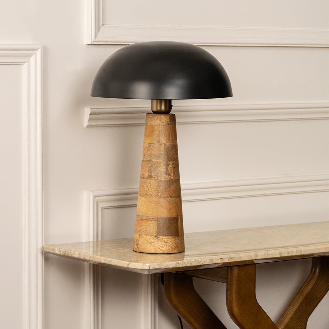 Black dome shade wooden cone table lamp on marble shelf with light off for artistic modern décor.