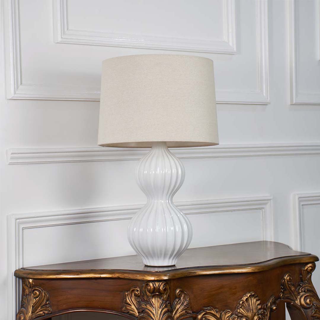 White ceramic table lamp with lights off against a plain white background focusing on its artistic form and elegant aesthetic.