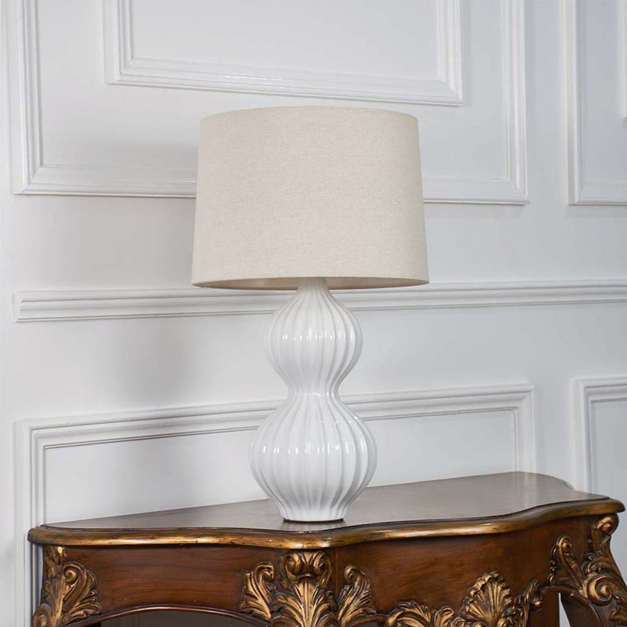 White ceramic table lamp with lights off against a plain white background focusing on its artistic form and elegant aesthetic.