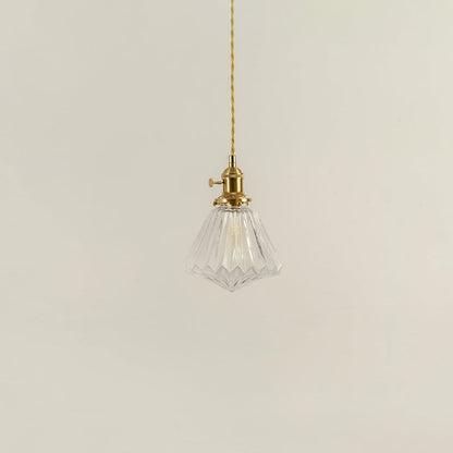 Unlit clear glass pendant light with golden brass holder hanging on yellow cord for sophisticated home decor appeal.