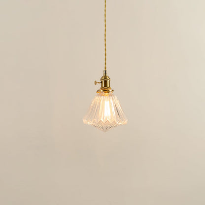 Clear glass pendant light with brass holder glowing softly on white background for elegant living room lighting.