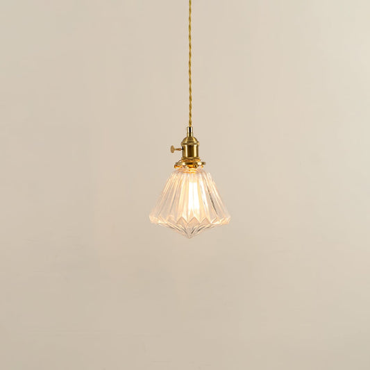 Clear glass pendant light with brass holder glowing softly on white background for elegant living room lighting.